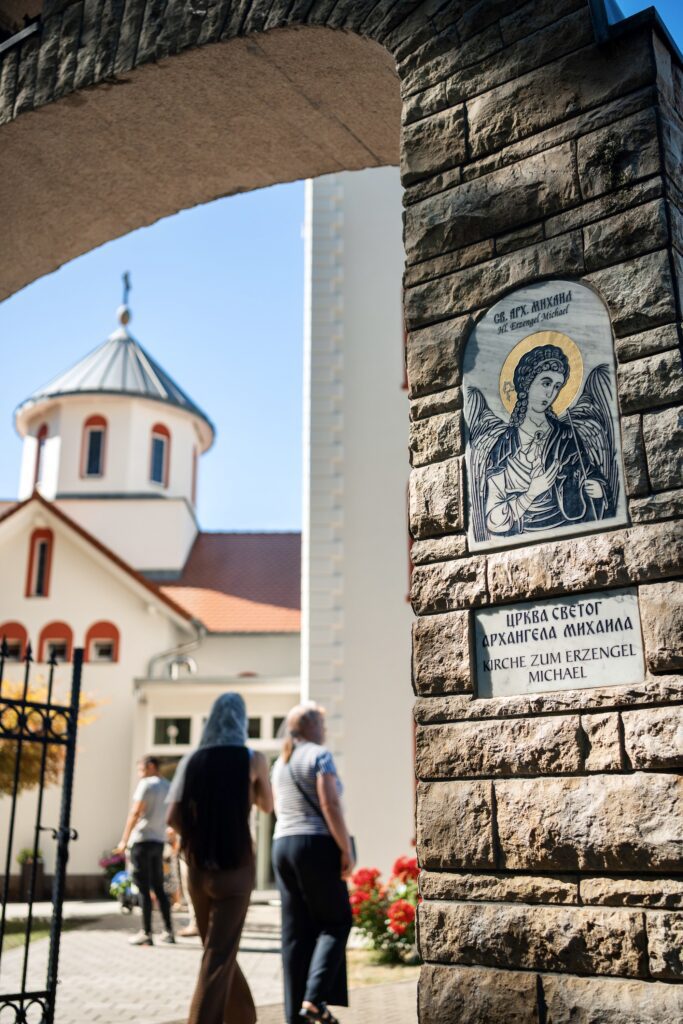 Visitors walking through the entrance of St. Michael's Church, showcasing its architectural details and religious iconography.