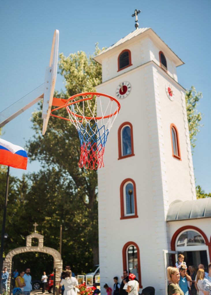 A vibrant basketball hoop in front of a charming white church, showcasing community engagement and outdoor activities.