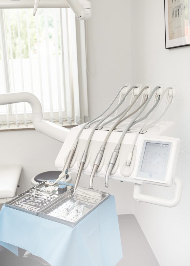 Modern dental equipment and instruments arranged on a tray in a bright dental office setting.